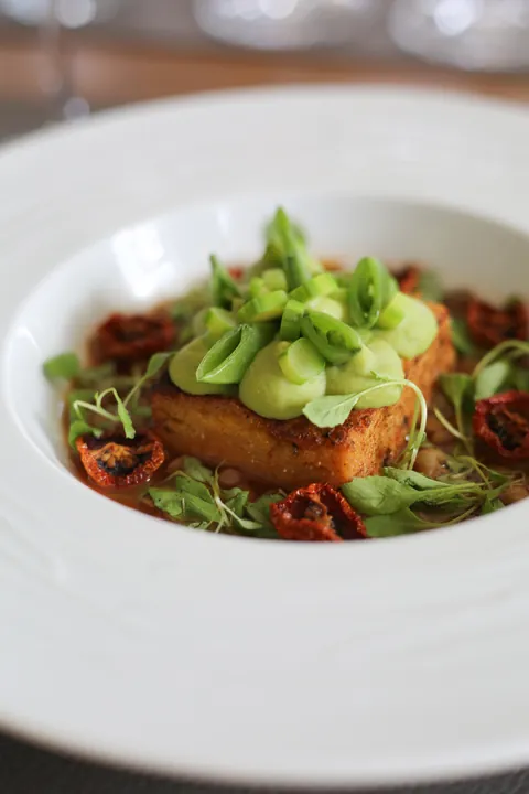 Spiced polenta cake with pea purée, lentils and a tomato and citrus broth