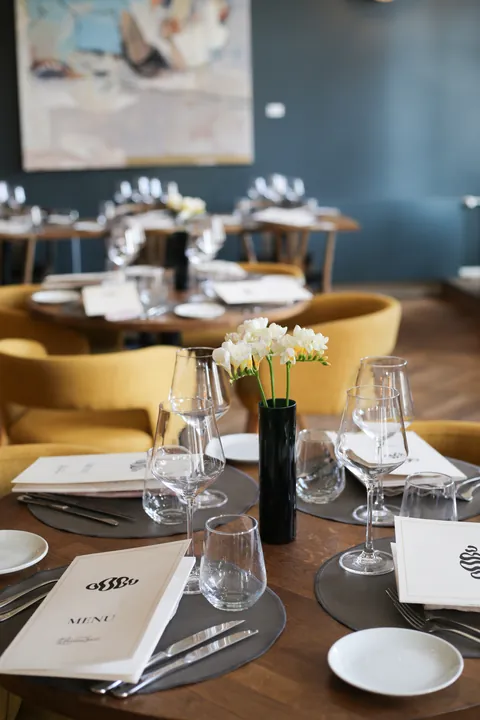 A laid table with the OOBU menu card and a yellow armchair