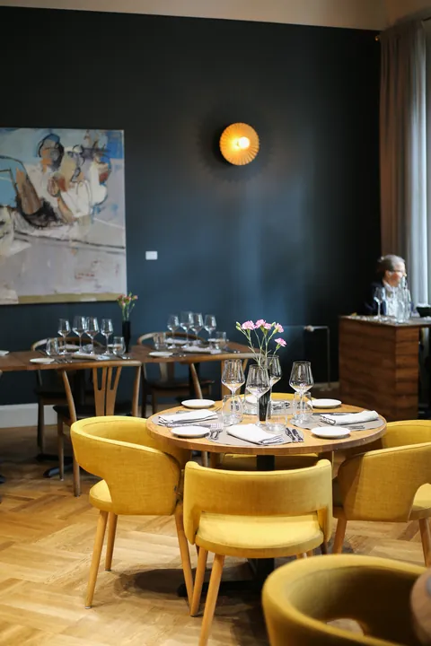 A round laid table and yellow armchairs beneath an artwork