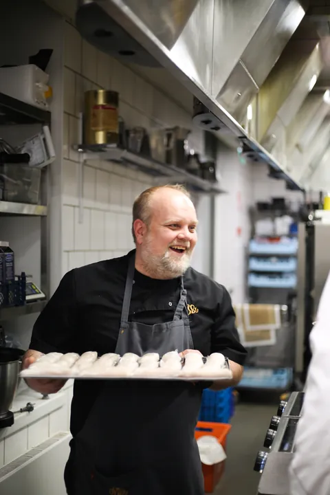 A chef carrying a tray of small plates
