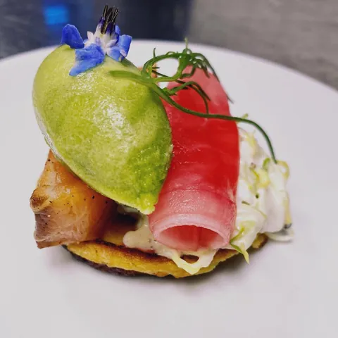 A course with a potato base, fish and a green sorbet